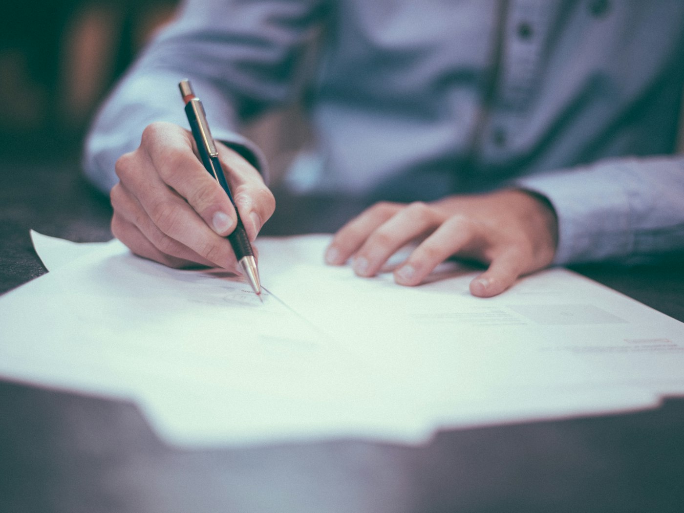 A person carefully reviewing and writing on documents