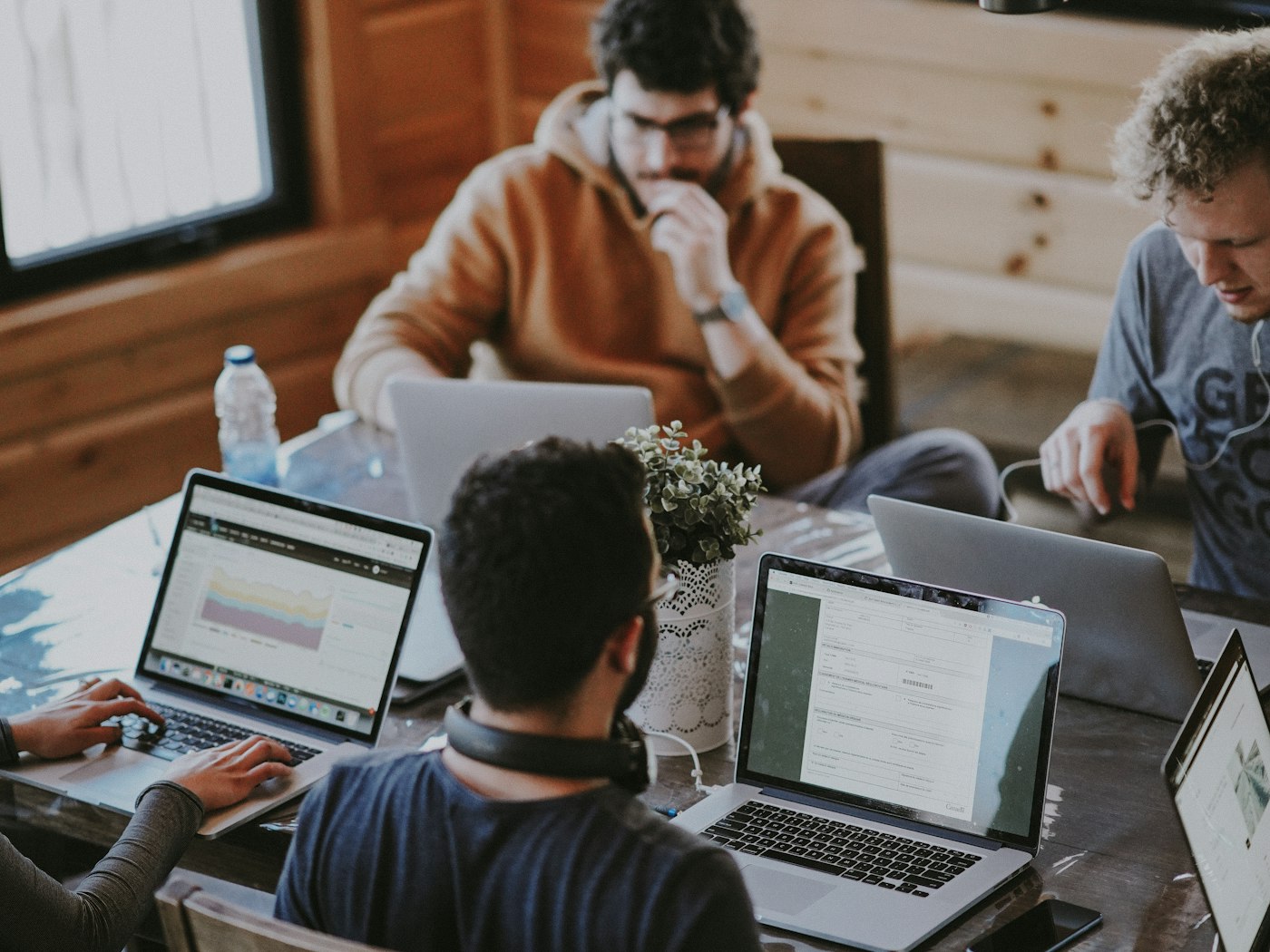 Professionals collaborating around a table with laptops